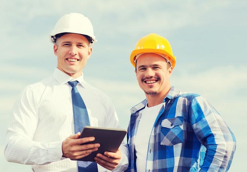 Quality assurance managers reviewing inspection data on mobile devices on a construction site