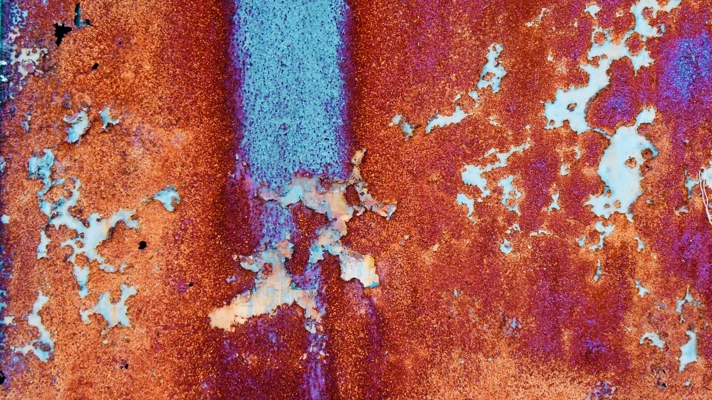Engineer using a tablet to inspect corroded pipework in an industrial facility