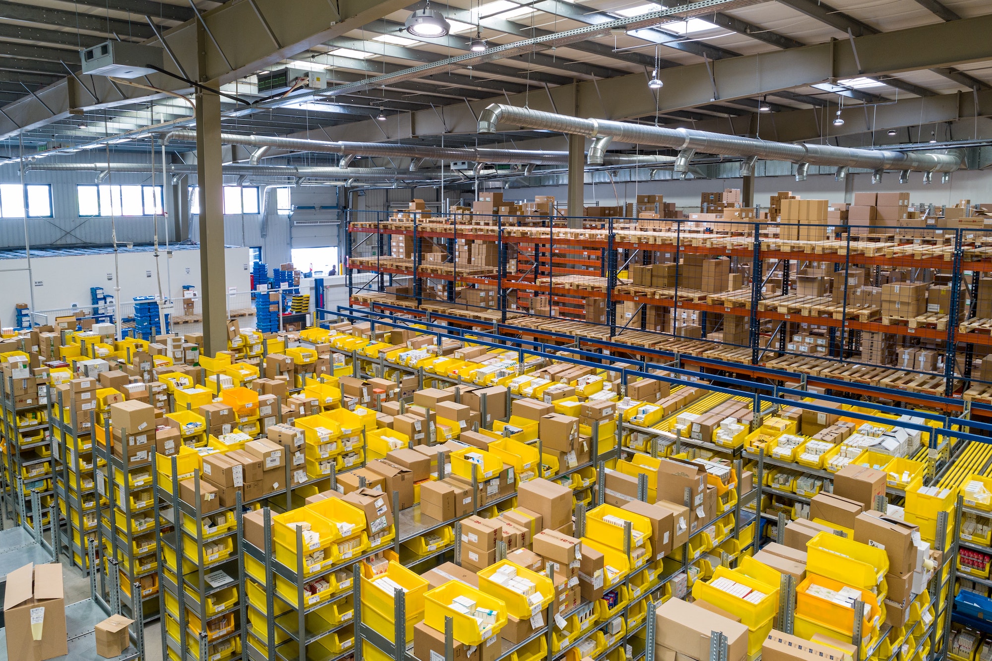 Inspector examining tall warehouse racking with a mobile device, conducting a digital racking safety inspection