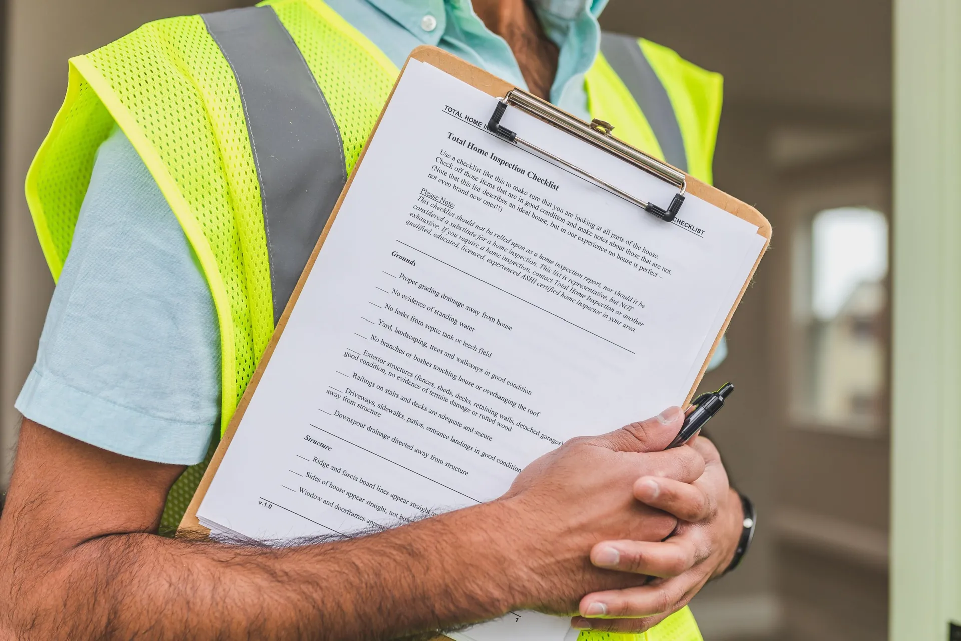 Inspector in a high-visibility vest holding a printed inspection checklist on a clipboard with a pen