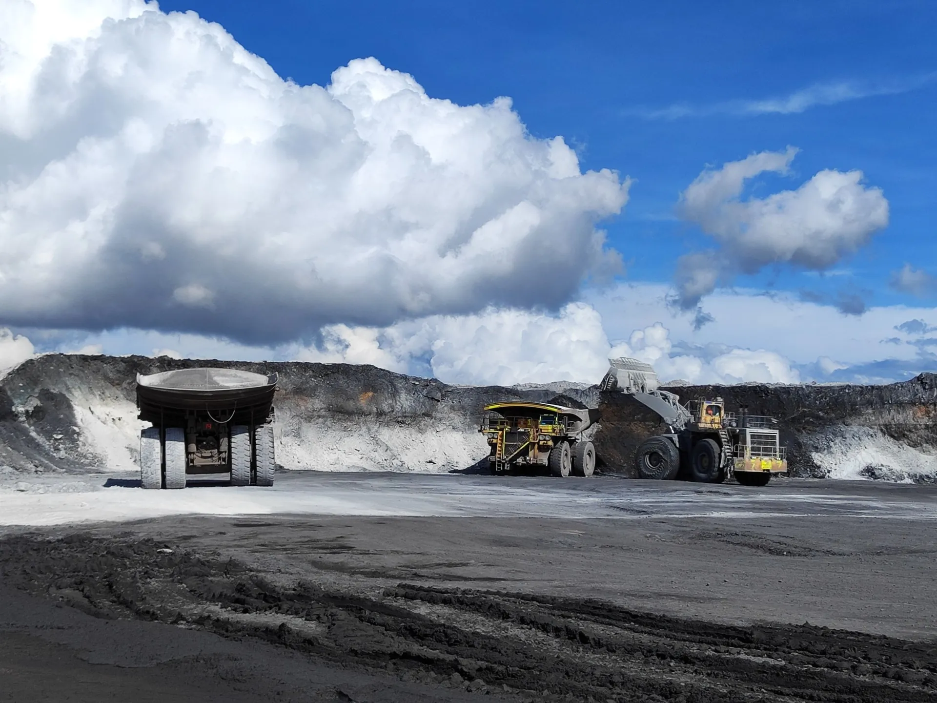 Large wheel loader filling a haul truck while a second truck waits at an open-cut coal mine