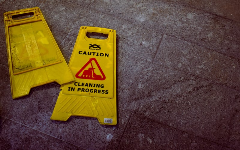 Worker recording safety inspection data on a mobile device at a facility entrance, replacing paper logbooks