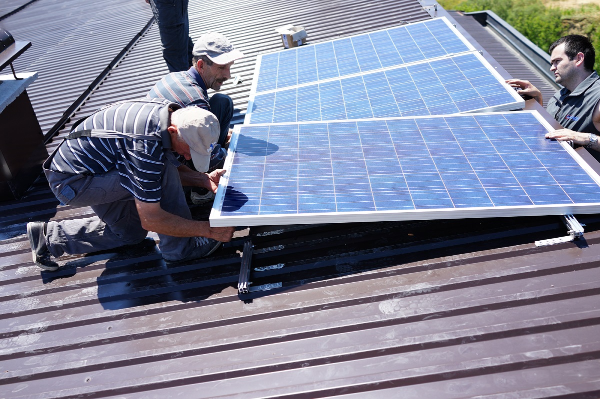 Solar technician inspecting photovoltaic panel connections and wiring on a rooftop installation