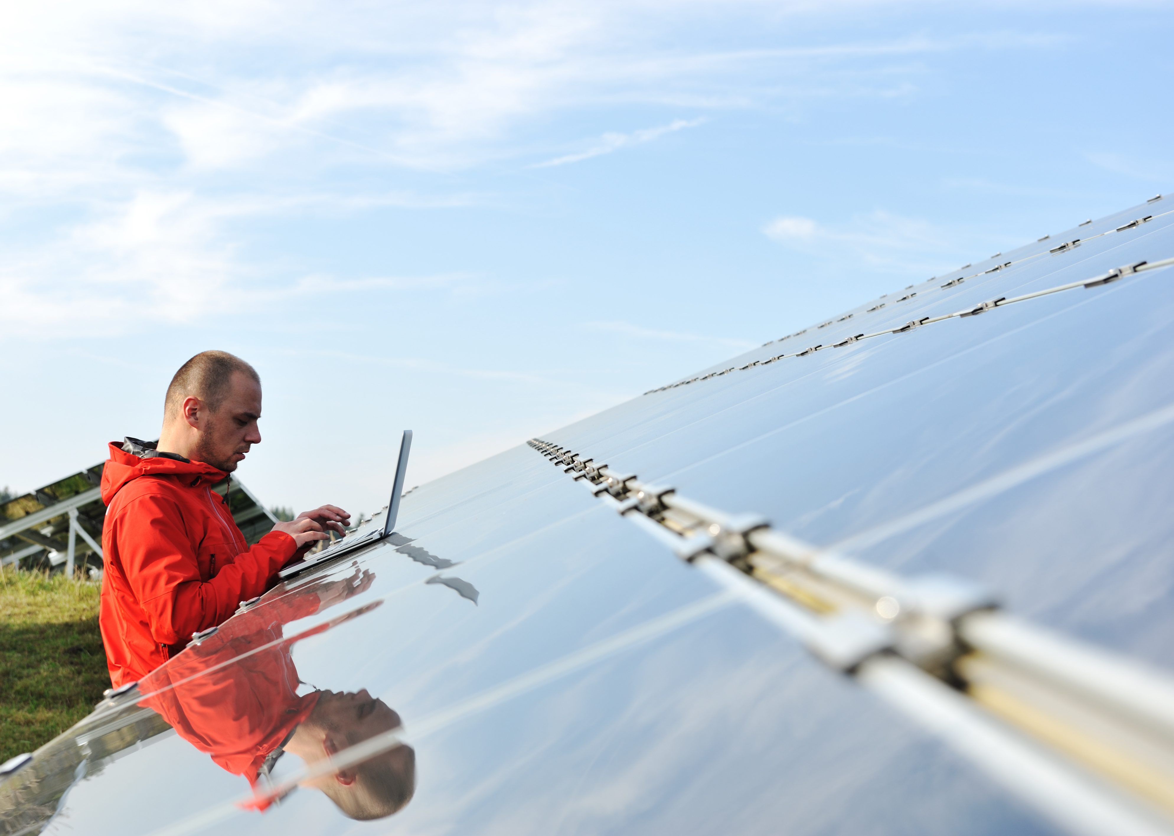 Solar panel array being inspected by a technician with a tablet, checking compliance with Australian Standard AS 5033